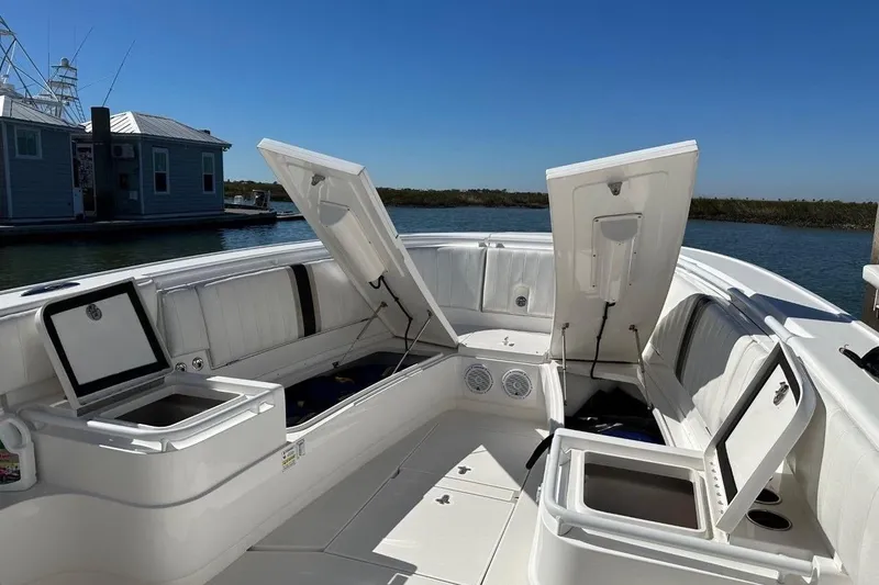 Slide: The Image of 2013 Intrepid 375 Center Console boat with open storage compartments, docked by a houseboat. - 24
