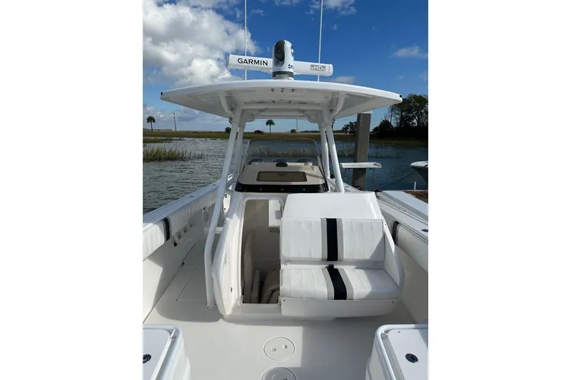 Slide: The Image of 2013 Intrepid 375 Center Console boat with white seating and Garmin radar, docked by a lake. - 15