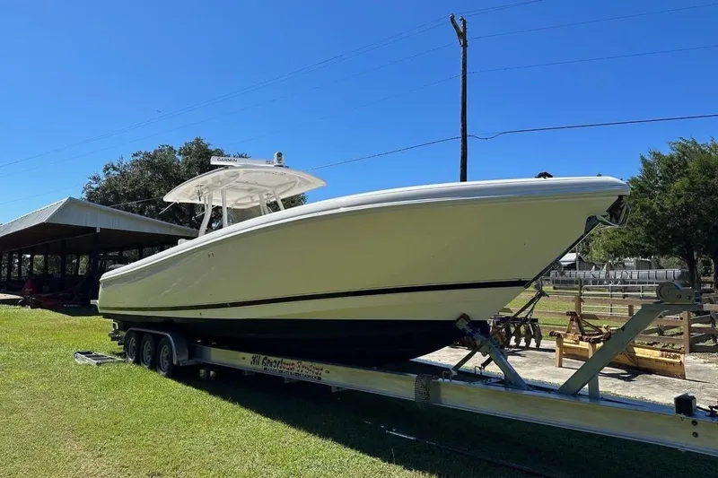 Slide: The Image of 2013 Intrepid 375 Center Console boat on trailer, parked outdoors under clear blue sky. - 1