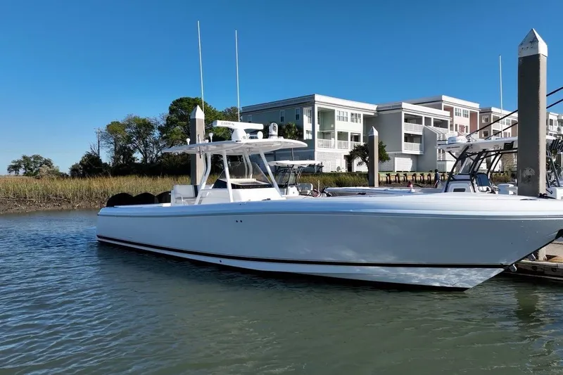 The Image of 2013 Intrepid 375 Center Console boat docked near modern waterfront buildings. - 3