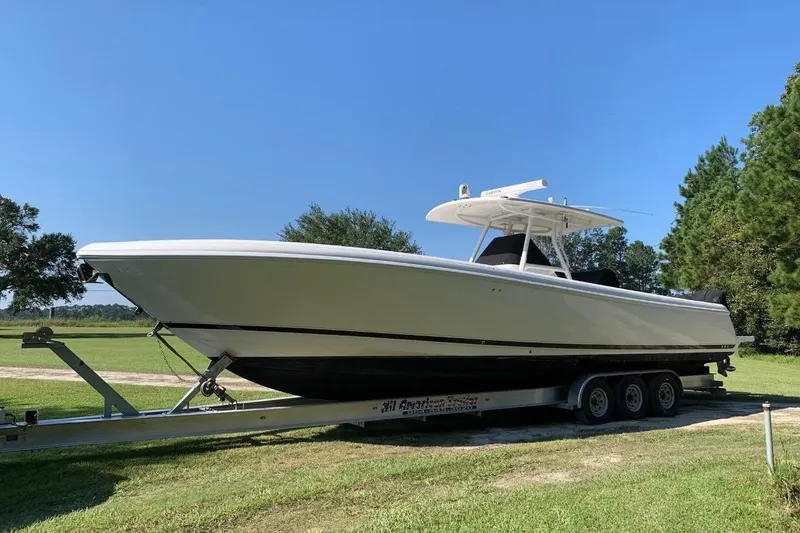 Slide: The Image of 2013 Intrepid 375 Center Console boat on trailer, parked on grassy area under clear blue sky. - 0