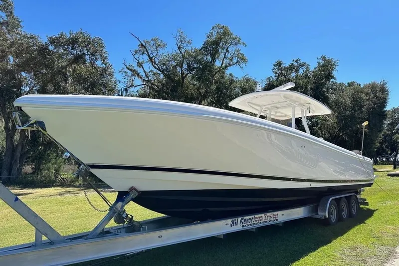Slide: The Image of 2013 Intrepid 375 Center Console boat on trailer, parked on grass under clear blue sky. - 2
