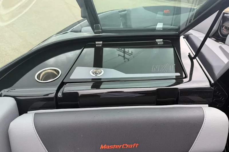 Slide: The Image of 2025 MasterCraft NXT23 boat interior with sleek black dashboard and cup holder. - 13
