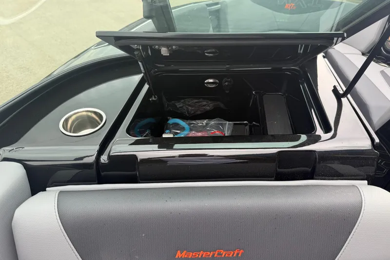 Slide: The Image of 2025 MasterCraft NXT23 boat interior with open storage compartment and cup holder. - 14
