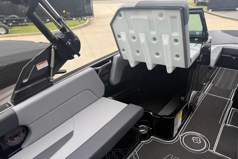 Slide: The Image of 2025 MasterCraft NXT23 boat interior with gray seating and storage compartment. - 15