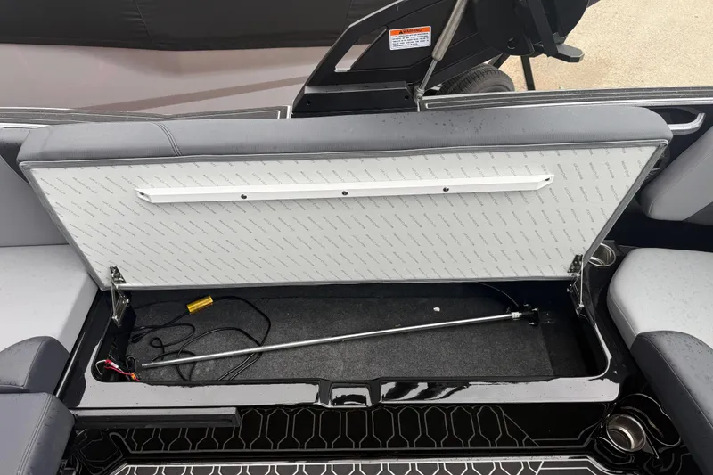 Slide: The Image of 2025 MasterCraft NXT23 boat storage compartment with open lid, showcasing interior space and wiring. - 18