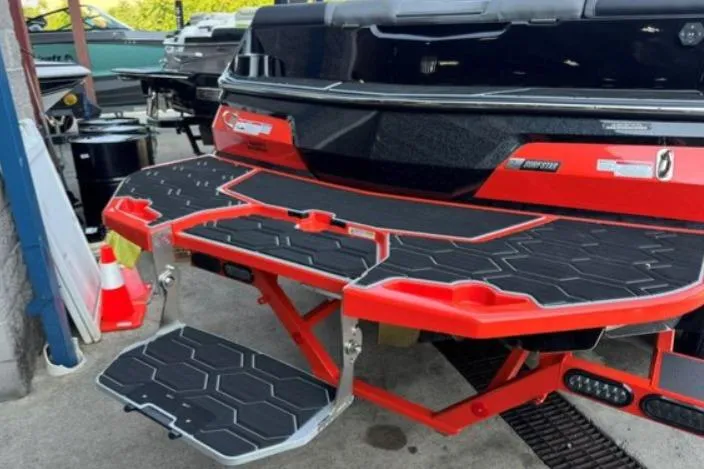 Slide: The Image of 2025 MasterCraft NXT23 boat with red and black swim platform in a marina setting. - 30