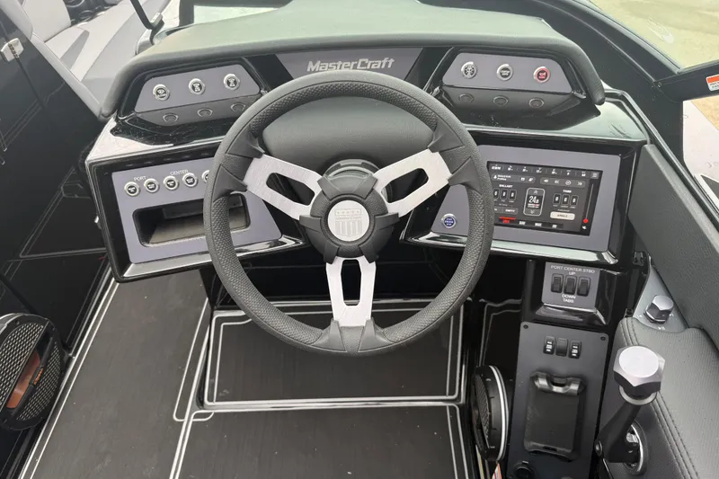 Slide: The Image of 2025 MasterCraft NXT23 boat dashboard with steering wheel and digital controls. - 7
