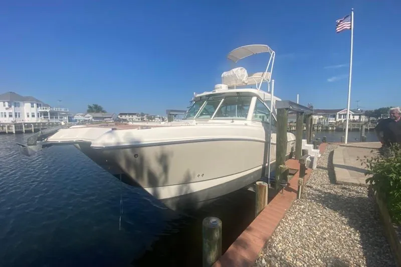 The Image of 2017 World Cat 320 DC boat docked by waterfront homes, clear sky, American flag. - 0