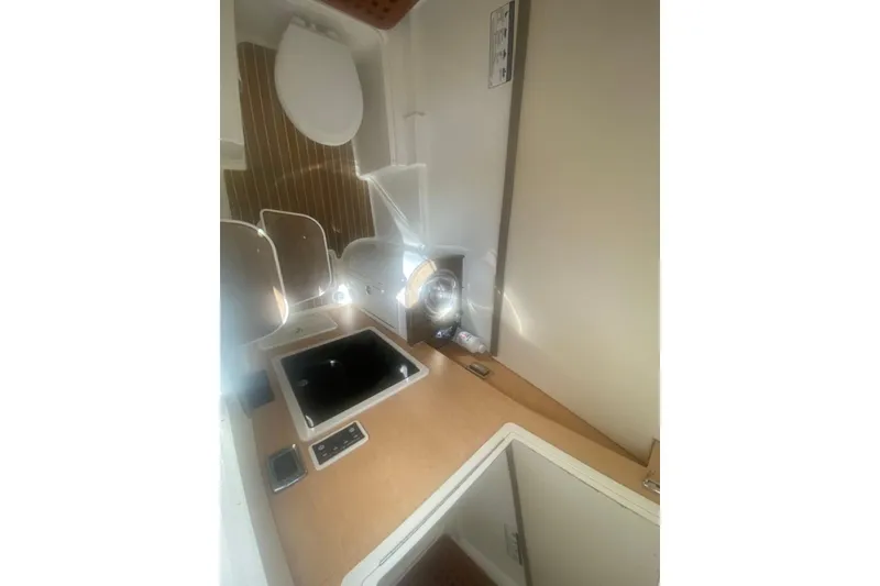Slide: The Image of Interior of 2017 World Cat 320 DC boat featuring compact kitchen and toilet area. - 7