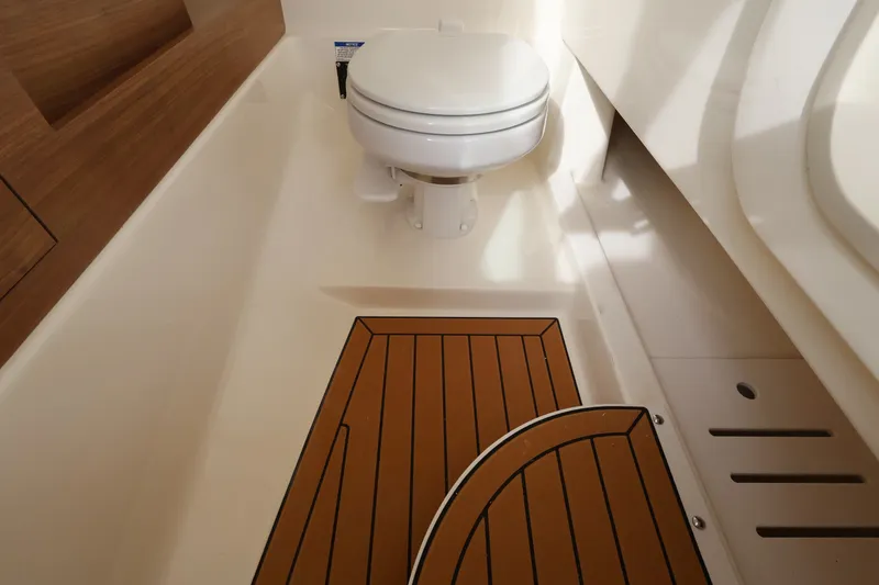 Slide: The Image of The image shows a toilet in a boat with wooden flooring and white walls. - 28