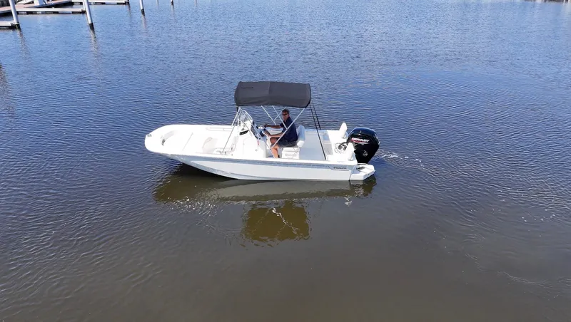 Slide: The Image of A 2027 Boston Whaler 170 Montauk on calm water, featuring a black canopy. - 11