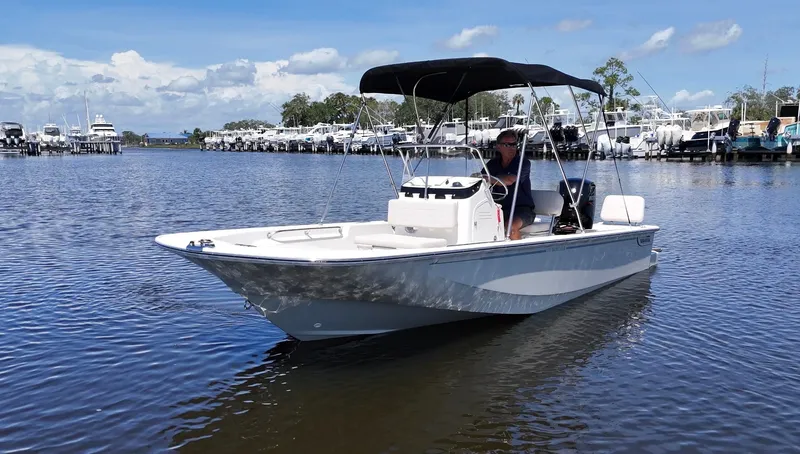 Slide: The Image of A 2027 Boston Whaler 170 Montauk on calm water. It features a black Bimini top. - 1
