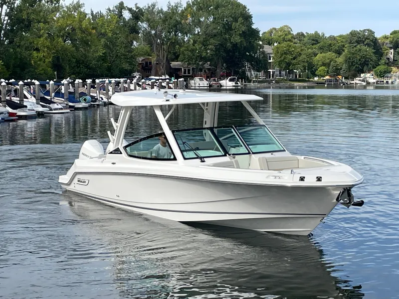 Slide: The Image of A 2027 Boston Whaler 280 Vantage cruising on a calm lake with a wooded shoreline. - 11