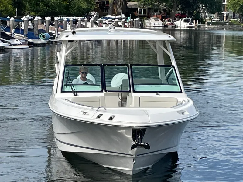 Slide: The Image of 2027 Boston Whaler 280 Vantage on calm water, with a person at the helm. - 10