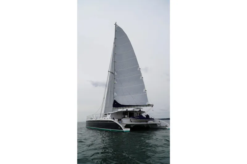 Slide: The Image of 2006 Lidgard Custom Catamaran sailing on open water with full sails. - 2