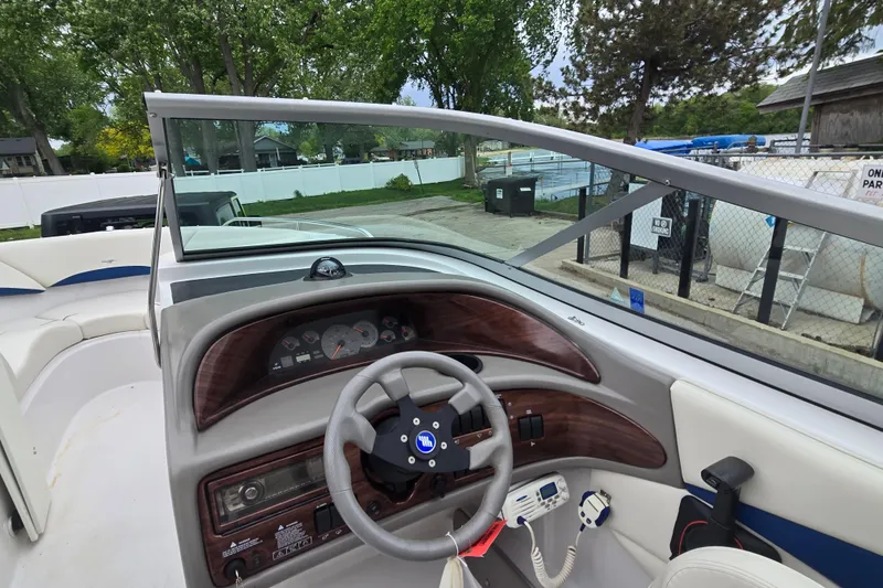 Slide: The Image of 2001 Four Winns 230 Horizon boat dashboard with steering wheel and gauges, docked outdoors. - 11