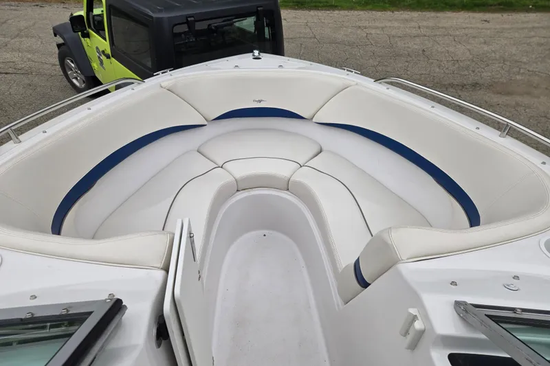 Slide: The Image of 2001 Four Winns 230 Horizon boat with white and blue cushioned seating, parked near a vehicle. - 13