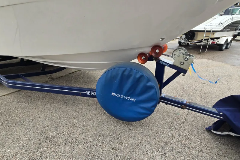 Slide: The Image of 2001 Four Winns 230 Horizon boat on trailer, featuring branded wheel cover. - 27