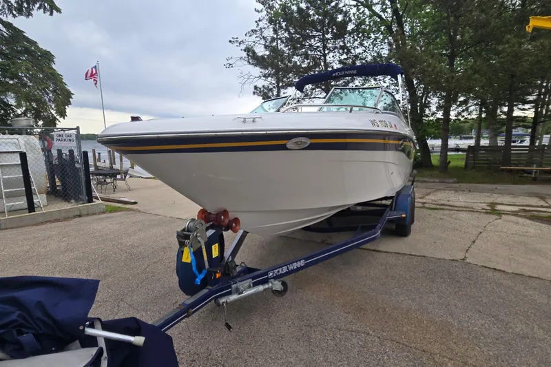 Slide: The Image of 2001 Four Winns 230 Horizon boat on trailer, parked near a lake. - 4