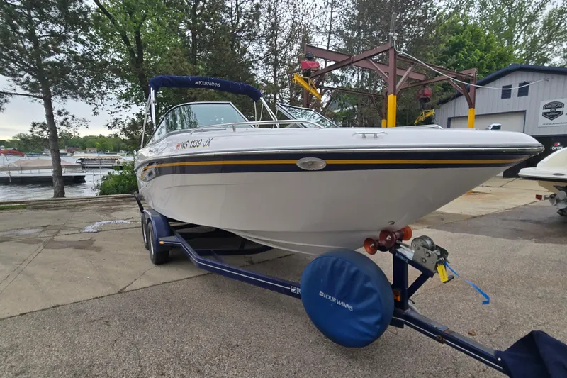 Slide: The Image of 2001 Four Winns 230 Horizon boat on trailer, parked near a marina. - 5