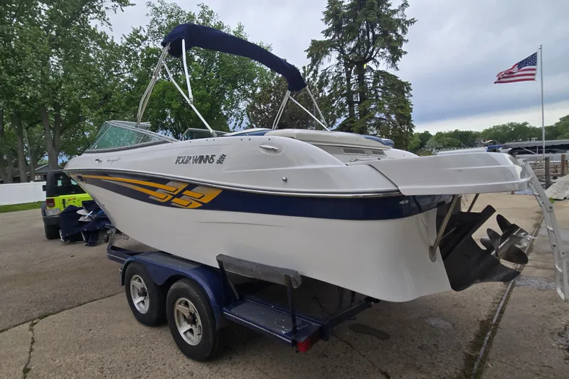 Slide: The Image of 2001 Four Winns 230 Horizon boat on trailer, parked outdoors with American flag. - 6