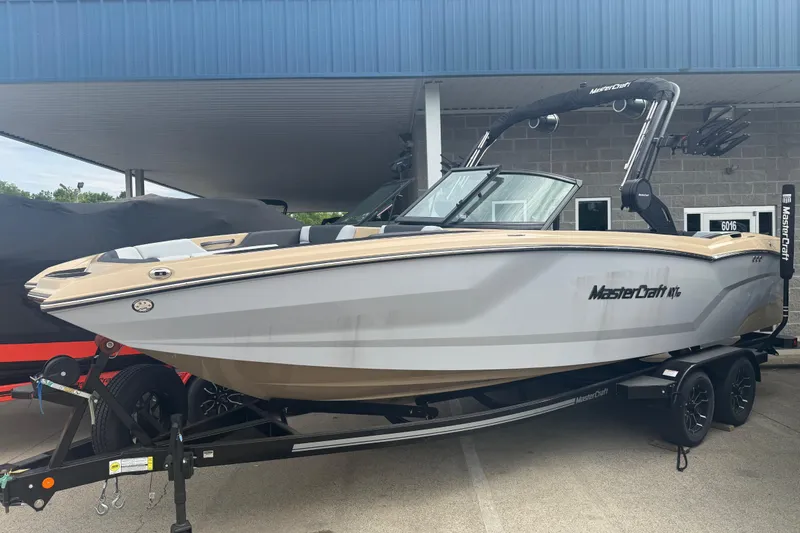 Slide: The Image of 2025 MasterCraft NXT24 boat on trailer under blue canopy. - 1