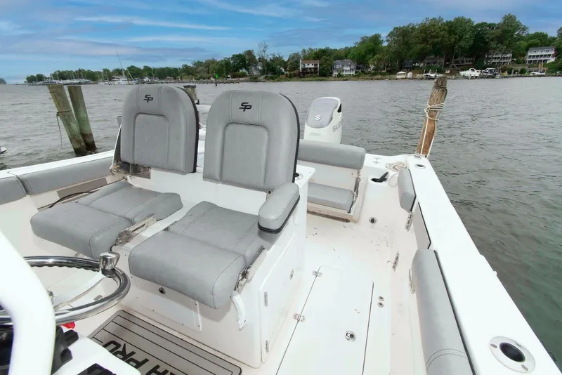 Slide: The Image of 2021 Sea Pro 259 Center Console boat interior with dual seats, docked by a scenic shoreline. - 11