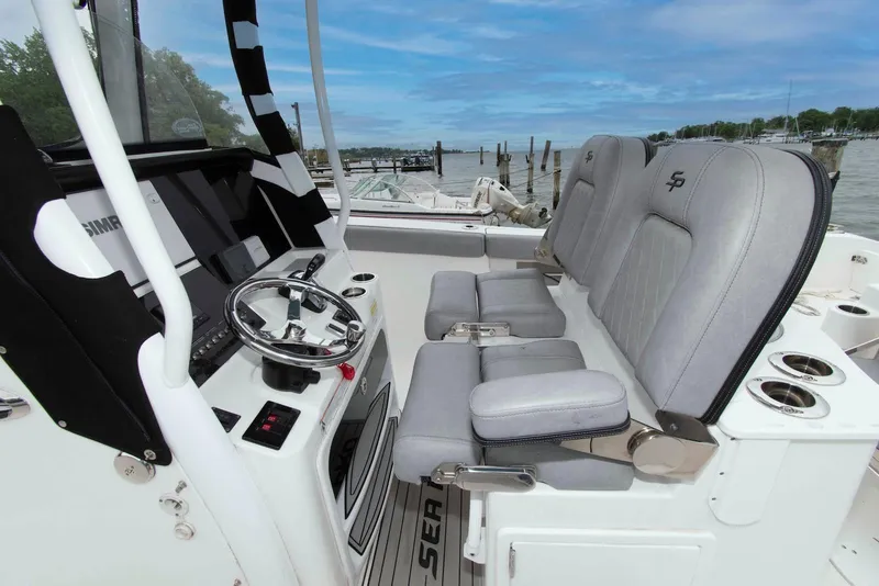 Slide: The Image of 2021 Sea Pro 259 Center Console boat interior with steering wheel and cushioned seats. - 5