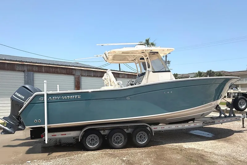 Slide: The Image of 2018 Grady-White Canyon 306 boat on trailer, featuring Yamaha engines, parked outdoors. - 2
