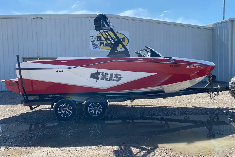 The Image of 2023 Axis T220 boat in red and white on a trailer outside a marine dealership. - 1