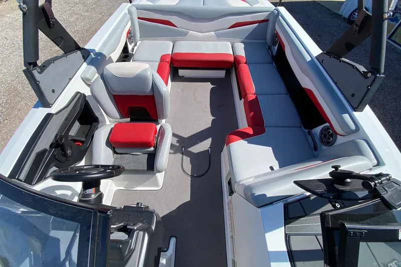 Slide: The Image of 2023 Axis T220 boat interior with red and gray seating, steering wheel, and spacious layout. - 10
