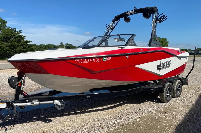 Slide: The Image of 2023 Axis T220 boat in red and white on a trailer, parked outdoors. - 3