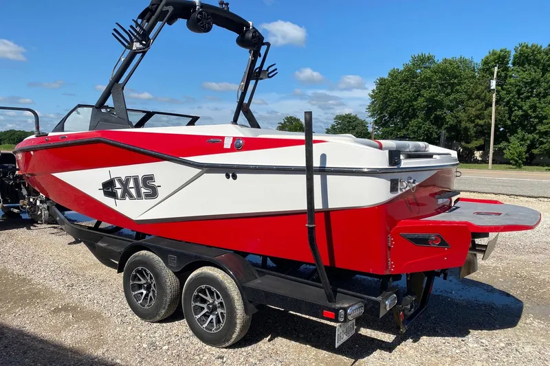 Slide: The Image of 2023 Axis T220 boat in red and white on a trailer, parked outdoors. - 4
