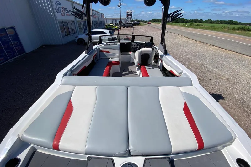 Slide: The Image of 2023 Axis T220 boat interior with red and gray seating, parked near dealership. - 7