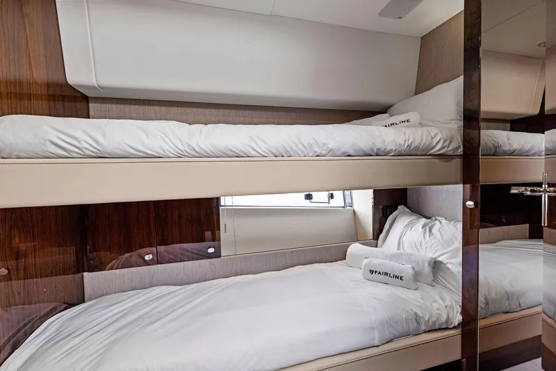 Slide: The Image of 2025 Fairline Targa 50 GT yacht cabin with luxurious bunk beds and elegant wood paneling. - 42