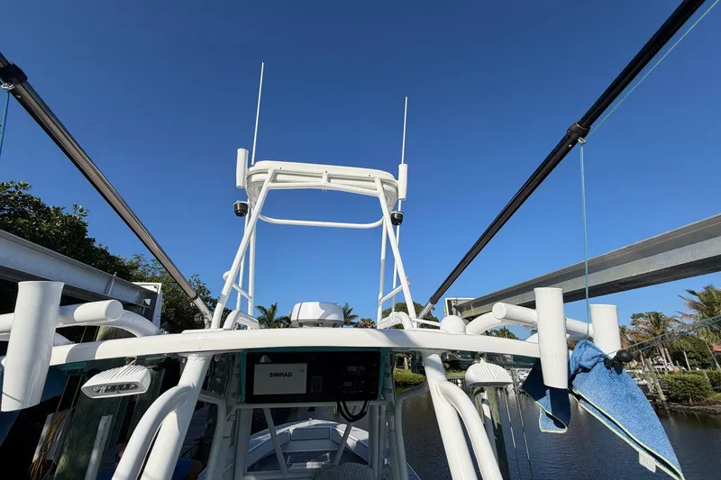 Slide: The Image of 2002 Regulator 26 Center Console boat with T-top and electronics, docked under clear blue sky. - 11