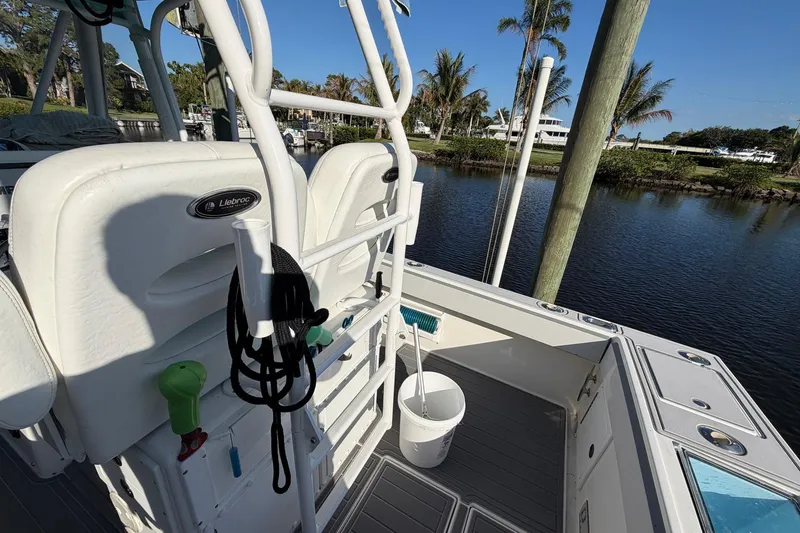 Slide: The Image of 2002 Regulator 26 Center Console boat with white seating, docked by a serene waterfront. - 15