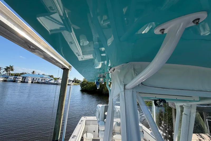 Slide: The Image of 2002 Regulator 26 Center Console boat with turquoise canopy, docked by a serene waterfront. - 17