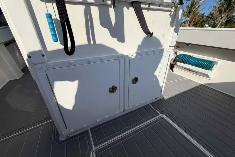 Slide: The Image of 2002 Regulator 26 Center Console boat deck with storage compartments and coiled hose. - 21