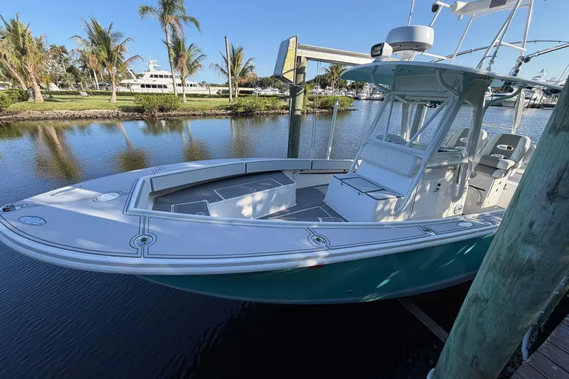 Slide: The Image of 2002 Regulator 26 Center Console boat docked by palm trees and calm water. - 3