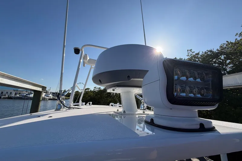 Slide: The Image of 2002 Regulator 26 Center Console boat with radar and spotlight, docked under clear sky. - 7