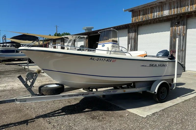 Slide: The Image of 2005 Sea Hunt Triton 186 boat on trailer, parked near wooden building. - 7