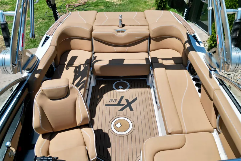 Slide: The Image of 2020 MasterCraft XT22 boat interior with tan seating and teak flooring. - 14