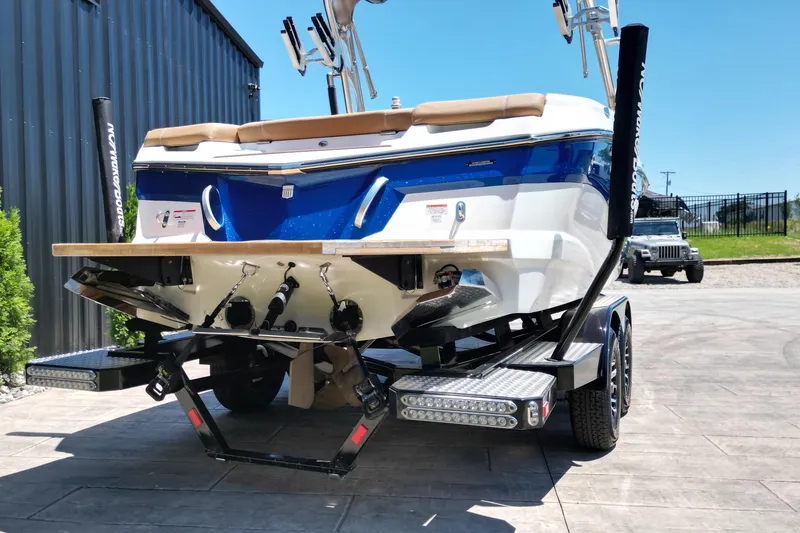 Slide: The Image of 2020 MasterCraft XT22 boat on trailer, blue and white design, parked outdoors. - 16