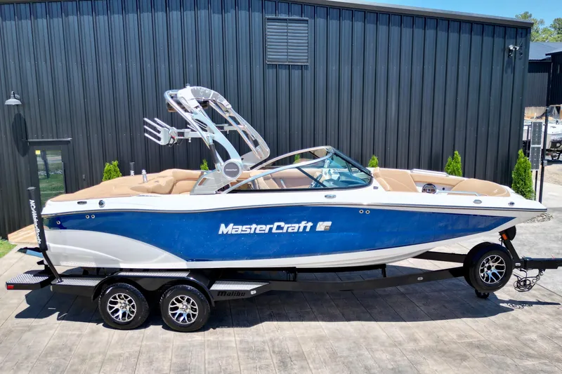 Slide: The Image of 2020 MasterCraft XT22 boat with blue and white exterior on a trailer. - 2