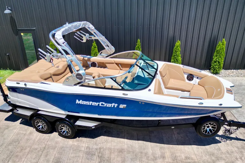 Slide: The Image of 2020 MasterCraft XT22 boat with blue and white exterior, tan interior, on a trailer. - 4