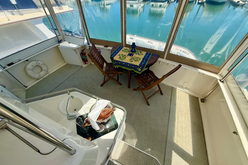 Slide: The Image of 2000 Sea Ray 380 Aft Cabin yacht interior with table, chairs, and marina view. - 4