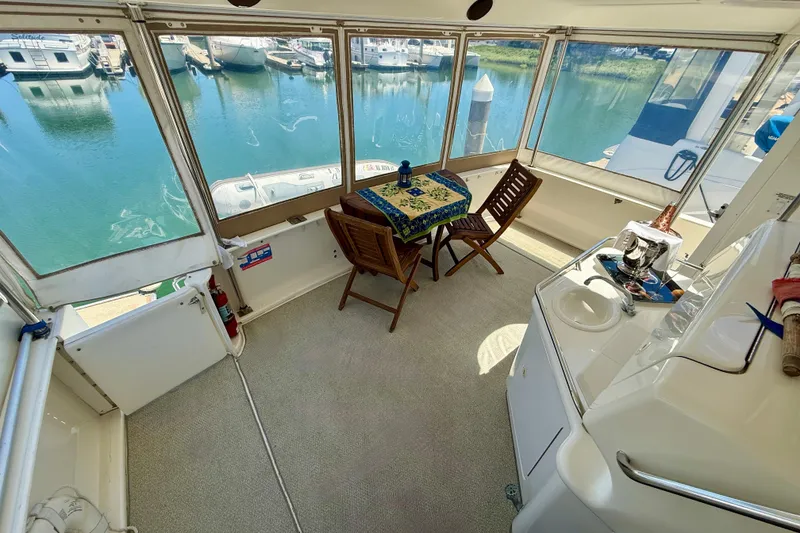 Slide: The Image of 2000 Sea Ray 380 Aft Cabin interior with table, chairs, and marina view. - 5