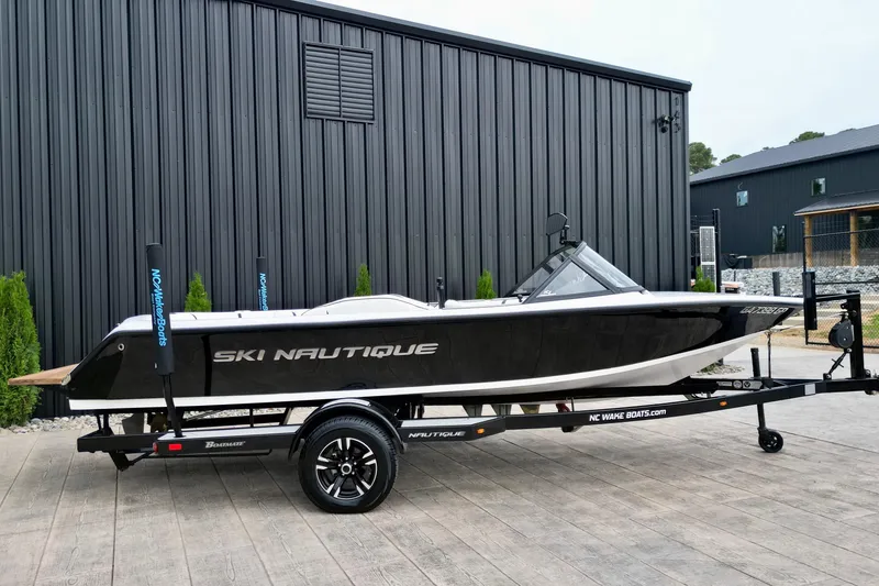 Slide: The Image of 1994 Nautique Ski Nautique boat on trailer, parked outside a modern building. - 2